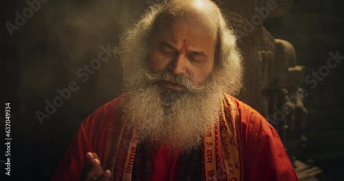 Slow-Motion Close-Up of Old Indian Monk Chanting in an Ancient Temple. The Senior Guru Sings Religious Songs, Humbly Chating Sacred Mantras, Showing Devotion and Love in Moment of Emotional Worship