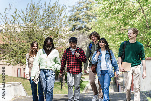 Generation Z Students with Backpacks Crossing the Park - A group of Generation Z students of diverse ethnicities, with backpacks on their shoulders and notebooks in hand, crosses the park.