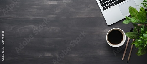 A black desk in an office with a laptop, smartphone, and other work supplies along with a cup of coffee. The view is from the top with space to input text. It is a designer's workspace with essential