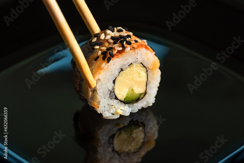 Traditional fresh sushi roll on black background with reflection.