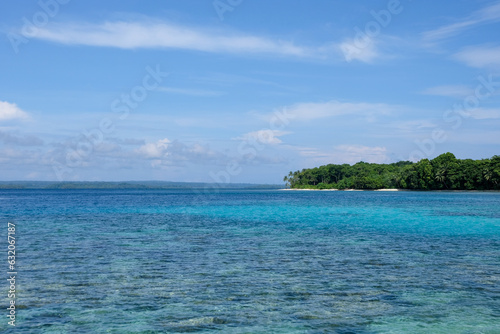Scenic view of stunning turquoise ocean water and a small tropical island with green trees in the Solomon Islands