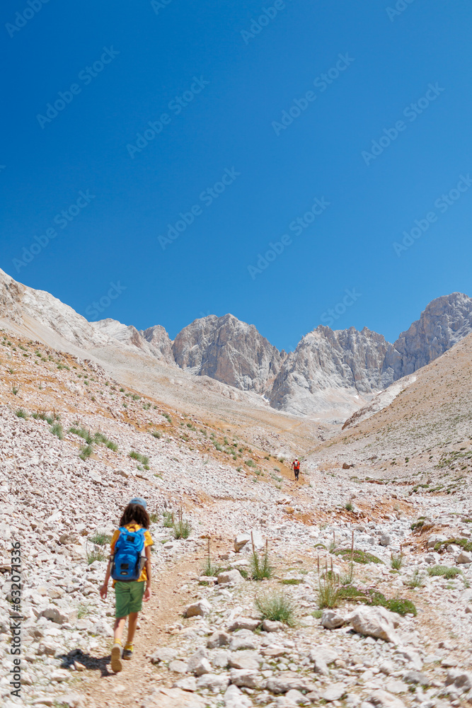 child travels in the mountains with a backpack. mountain hike in high mountains. Turkey.