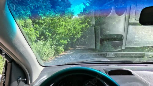 driving in a car on a bad road. travel by car. view from the driver's point of view. car cabin. man driving. tree tunnel on the road. beautiful road and nature. autotravel. photo