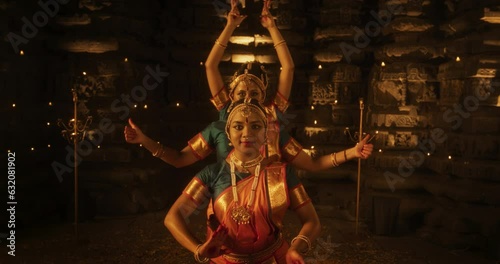 Slow Motion Portrait of Three Expressive Young Indian Dancers Performing Folk Dance Choreography Inside an Ancient Temple. Women in Traditional Clothes Dancing Bharatanatyam in Colourful Sari photo