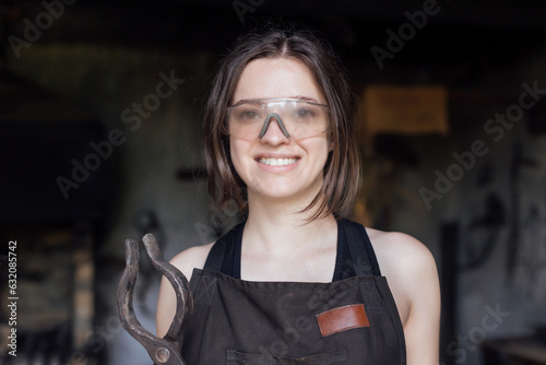 Fotografija Young woman blacksmith portraitin protective glasses in workshop