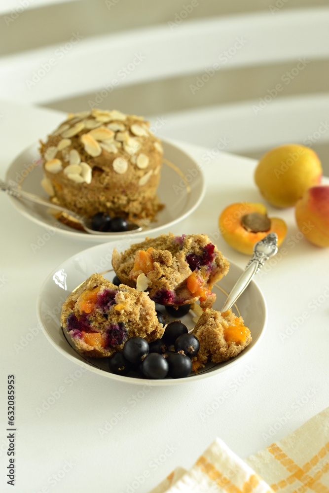 Muffins with apricots and black currants sprinkled with almond flakes, vertical