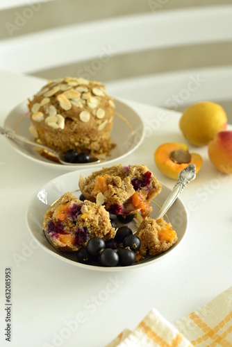 Muffins with apricots and black currants sprinkled with almond flakes, vertical