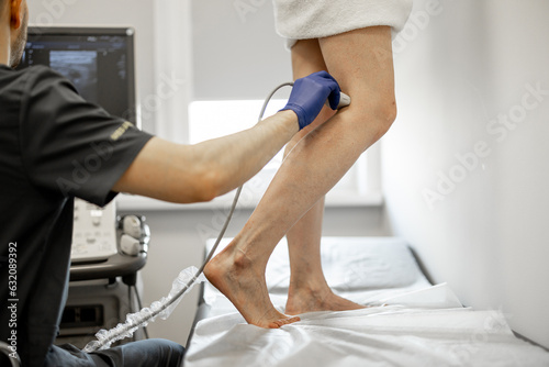 Ultrasound specialist is scanning the veins on a woman's leg, examining veins for varicose treatment photo