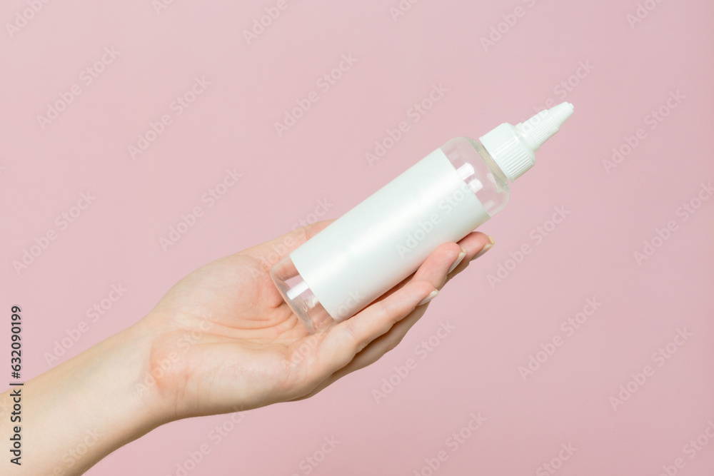 Cosmetic bottle in woman's hand. Cosmetic product branding mockup. Spa beauty treatment concept Cosmetic bottle in woman's hand. Cosmetic product branding mockup. Spa beauty treatment concept