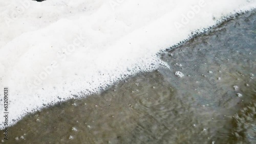 Texture of water and sand. Coast. Close up of white foam at sea beach. surf