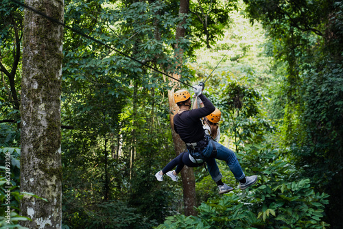 tourists wearing casual clothes on a zip line or awning experience in the Laos Asian rainforest.