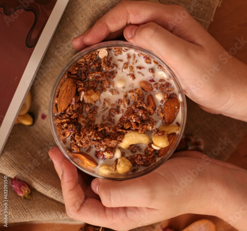 yogurt is poured into a transparent bowl with nut-flavored granola