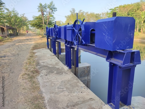 Sluice gates are buildings that function as water flow regulators for drainage, tapping, irrigation water traffic regulators, regulating the amount of water flowed into the irrigation channel system. photo