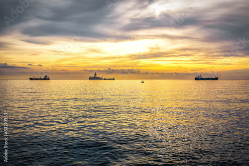 Anchored ships waiting their turn to enter in the port at sunrise
