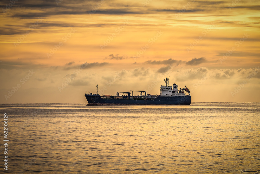 Industrial ship on anchor in the open sea at sunrise