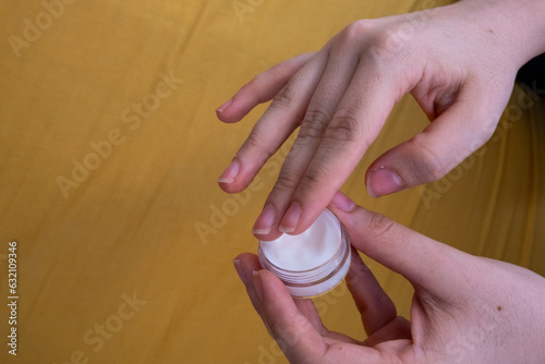 Preparándose para mimarse: Manos delicadas sosteniendo el bote de crema hidratante, listas para el cuidado personal photo