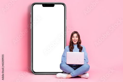 Full body portrait of excited amazed lady sit floor use netbook big empty space telephone display isolated on pink color background