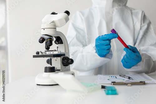 A doctor's hand holds a small vial with a blood test next to other samples. check your blood Close-up shot of a male scientist in a white uniform while working in a laboratory.