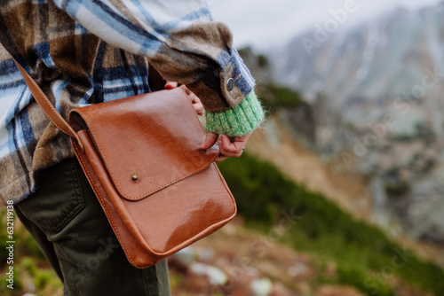 Woman weraring crossody bag during the hike in an autumn mountains.