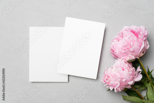 Wedding invitation card mockup with pink fresh peony flowers, blank card mock up on grey background, top view with copy space © nikavera
