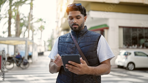 African american man using touchpad with relaxed expression at street