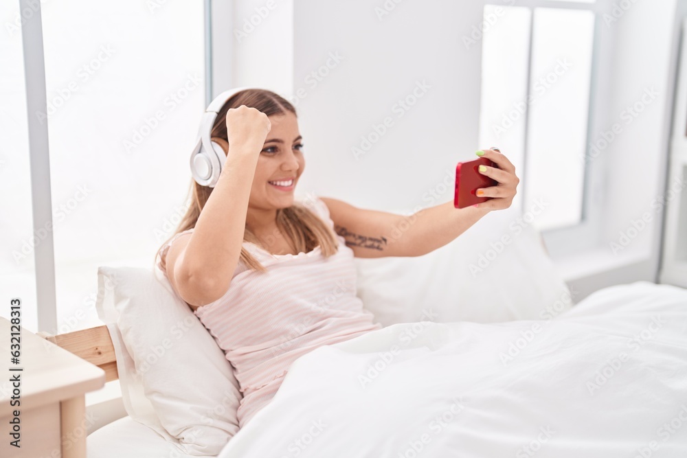 Young beautiful hispanic woman playing video game sitting on bed at bedroom Young beautiful hispanic woman playing video game sitting on bed at bedroom