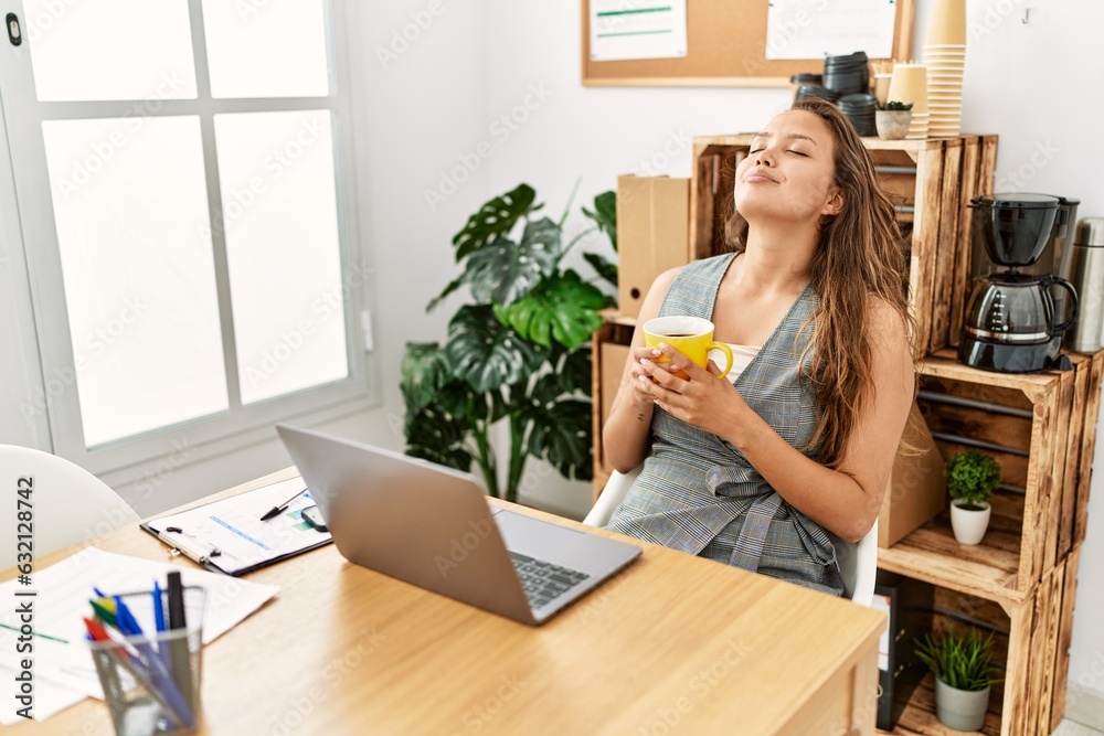 Young beautiful hispanic woman business worker using laptop drinking coffee at office Young beautiful hispanic woman business worker using laptop drinking coffee at office