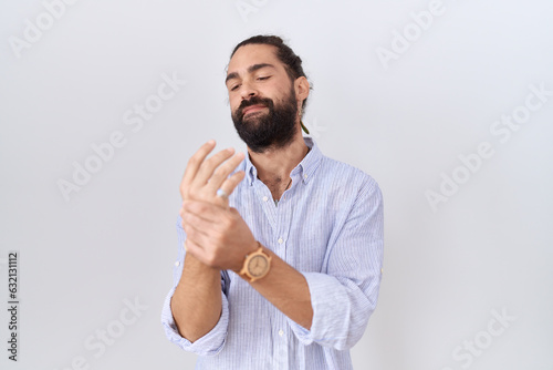 Hispanic man with beard wearing casual shirt suffering pain on hands and fingers, arthritis inflammation