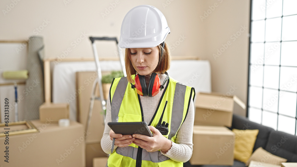 Young blonde woman architect using touchpad with serious expression at new home Young blonde woman architect using touchpad with serious expression at new home