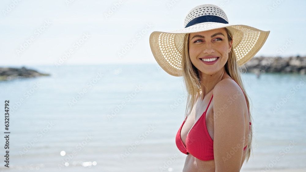 Young blonde woman tourist smiling confident wearing bikini and summer hat at beach