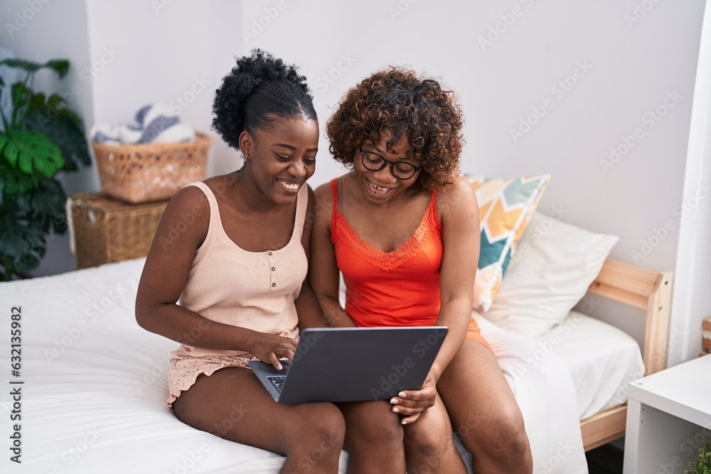 African american women mother and daughter using laptop at bedroom