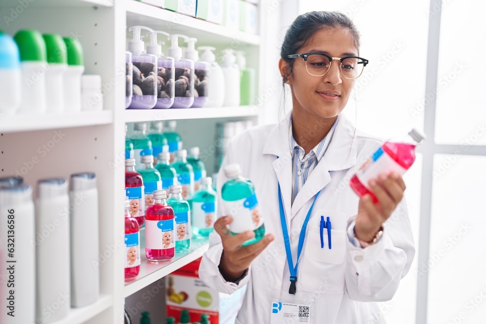 Young beautiful hispanic woman pharmacist smiling confident holding medication  bottles at pharmacy