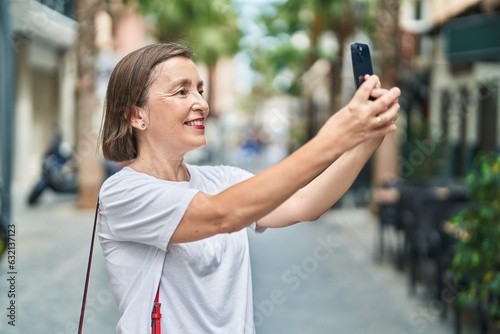 Middle age woman smiling confident making selfie by the smartphone at street