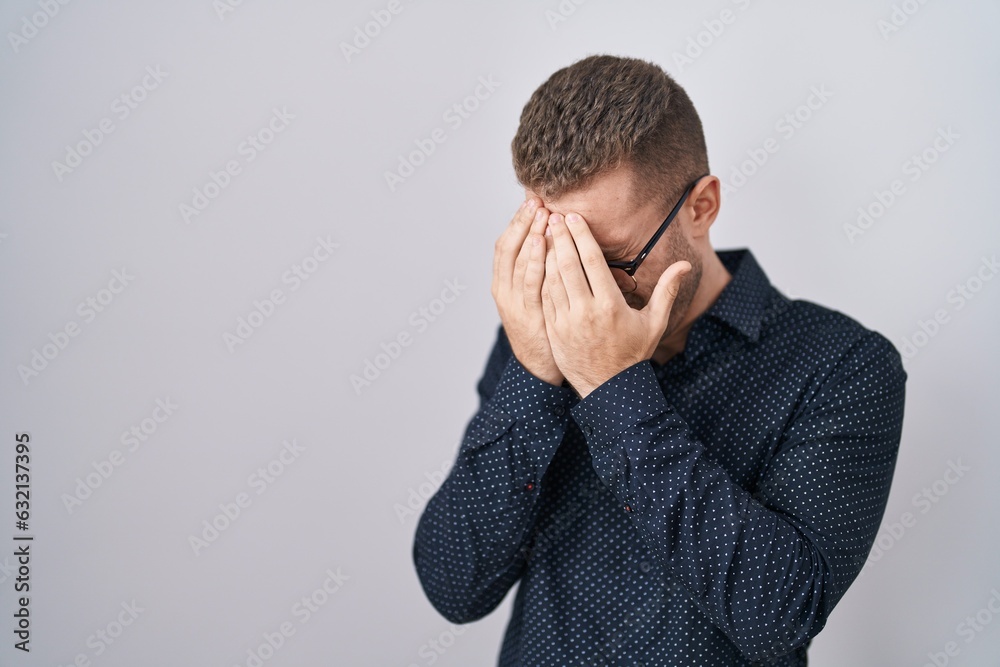 Young caucasian man standing over isolated background with sad expression covering face with hands while crying. depression concept.