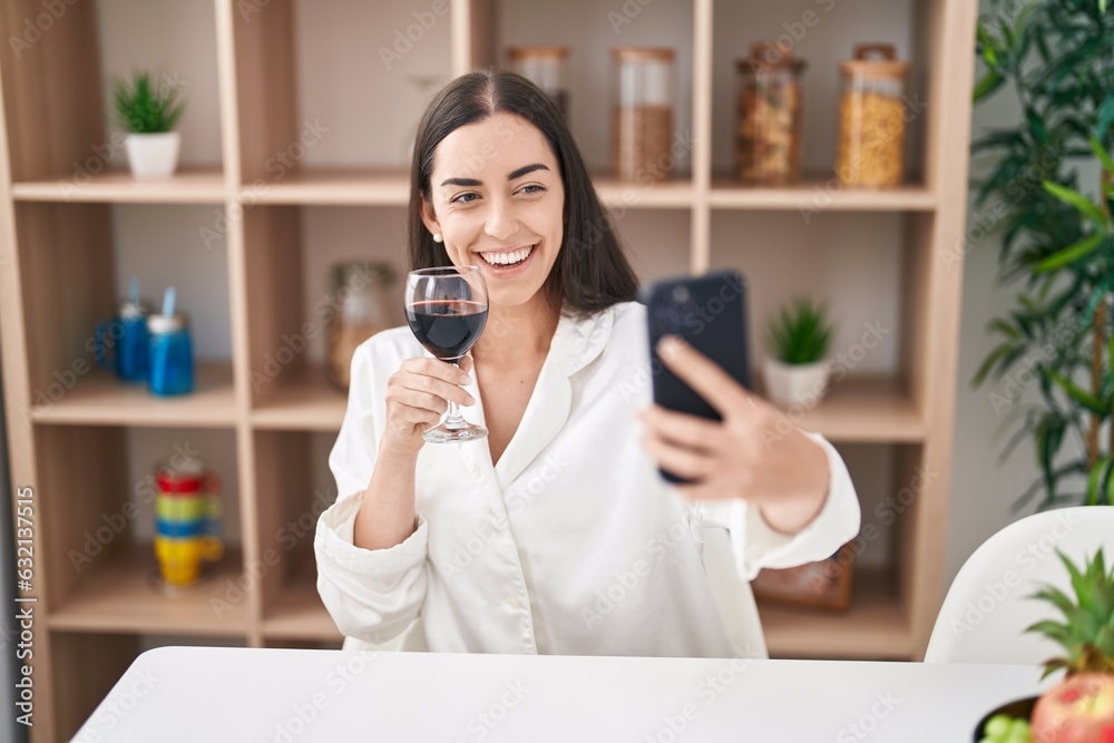 Young hispanic woman make selfie by the smartphone and drinking wine at home Young hispanic woman make selfie by the smartphone and drinking wine at home