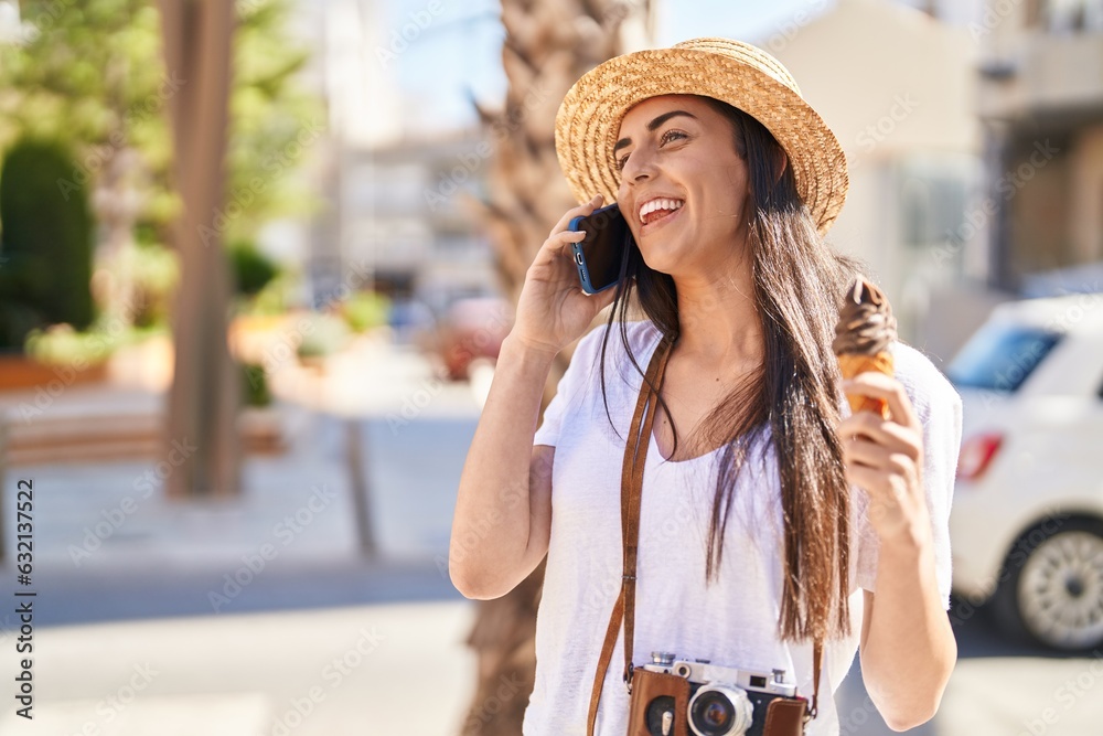 Young hispanic woman tourist talking on the smartphone eating ice cream at street
