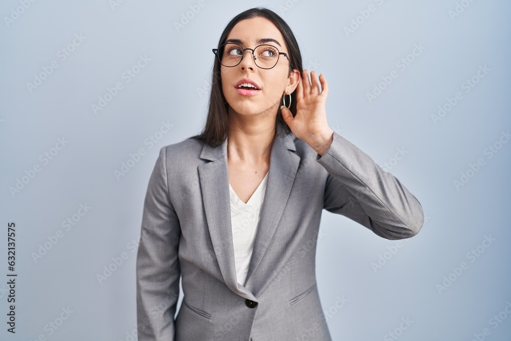 Hispanic business woman wearing glasses smiling with hand over ear listening an hearing to rumor or gossip. deafness concept. Hispanic business woman wearing glasses smiling with hand over ear listening an hearing to rumor or gossip. deafness concept.