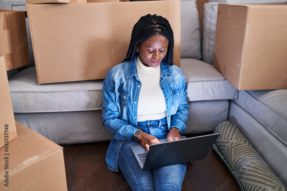 African american woman using laptop sitting on floor at new home African american woman using laptop sitting on floor at new home
