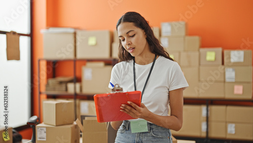 African american woman ecommerce business worker writing on document checking pacakges at office photo