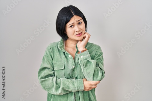 Принти на полотні Young asian woman standing over white background thinking worried about a questi