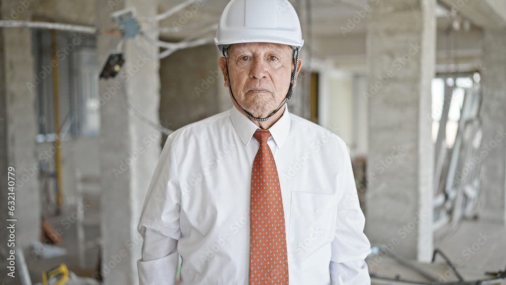 Senior grey-haired man architect standing with relaxed expression at construction site Senior grey-haired man architect standing with relaxed expression at construction site