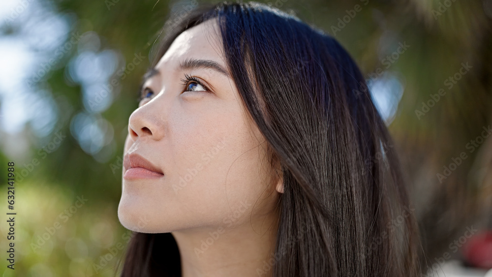 Young chinese woman looking to the sky with serious expression at park Young chinese woman looking to the sky with serious expression at park