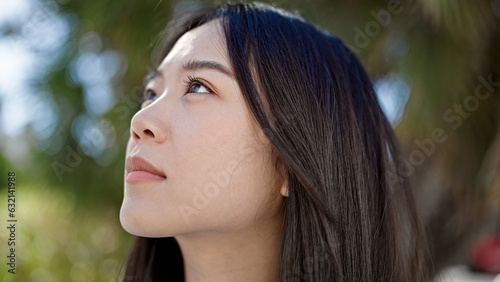 Young chinese woman looking to the sky with serious expression at park