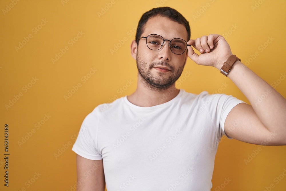 Hispanic man holding glasses thinking attitude and sober expression looking self confident Hispanic man holding glasses thinking attitude and sober expression looking self confident