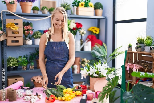 Young blonde woman florist make bouquet of flowers at florist store