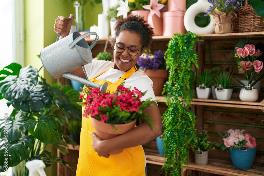 African american woman florist watering plant at flower shop