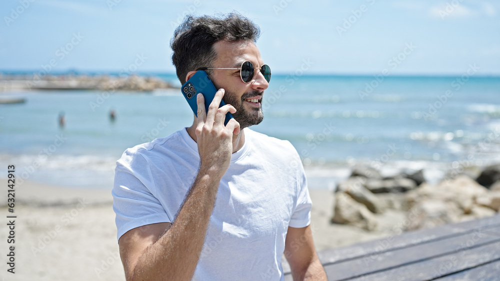 Young hispanic man smiling confident talking on the smartphone at seaside