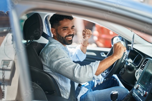 Young arab man sitting on car dancing at street