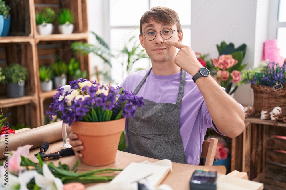Caucasian blond man working at florist shop pointing with hand finger to face and nose, smiling cheerful. beauty concept Caucasian blond man working at florist shop pointing with hand finger to face and nose, smiling cheerful. beauty concept