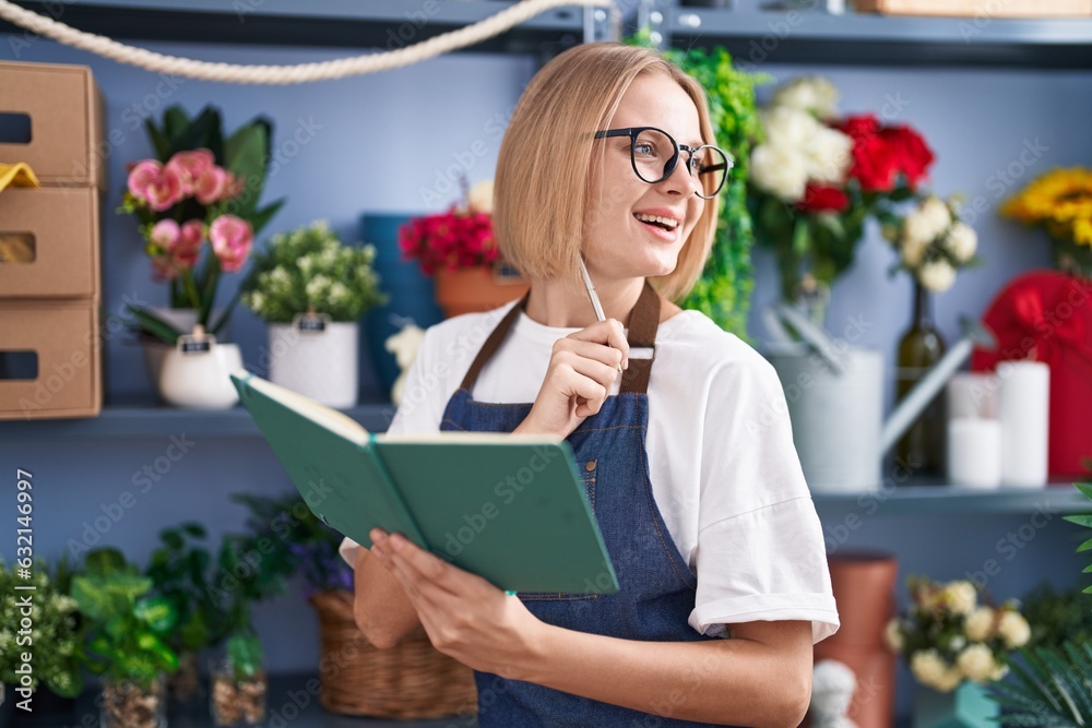 Young blonde woman florist smiling confident writing on notebook at florist shop Young blonde woman florist smiling confident writing on notebook at florist shop
